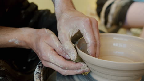 hands shaping a bowl on a pottery wheel