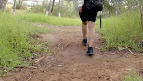 a person hikes on a dirt trail surrounded by green grass with copy space