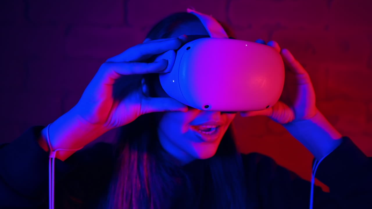 A young woman is excited while putting on VR glasses, controllers. Red and blue illumination. Slow motion