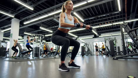 woman performing dumbbell squats in a modern gym