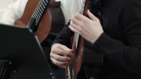 tocando la guitarra clásica, un hombre en primer plano y una mujer en segundo plano