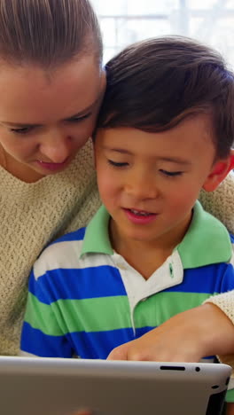 madre e hijo usando tableta digital en la sala de estar