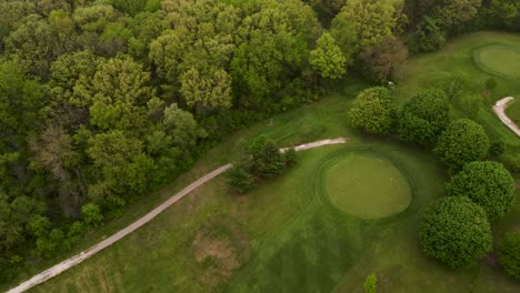 Vista-Aérea-Giratoria-De-La-Colina-Del-Campo-De-Golf-Junto-A-Un-Bosque-Verde