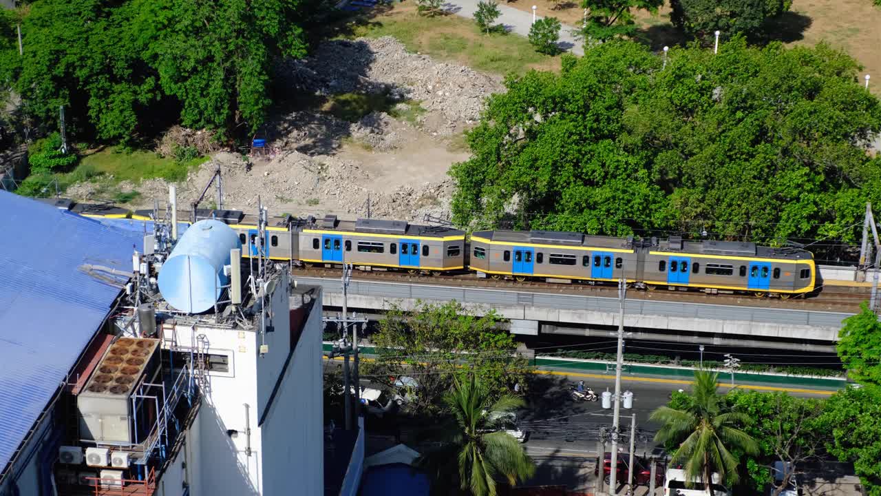 Aerial view of public transport train carriages and traffic on highway in capital city of Manila Philippines