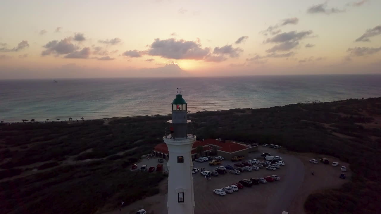 un turista de pie en la parte superior del faro de california en aruba durante la puesta de sol de la hora dorada