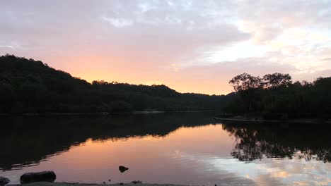 peaceful scenery of nature with forested mountain reflected on calm lake in woronora river, australia during sunset