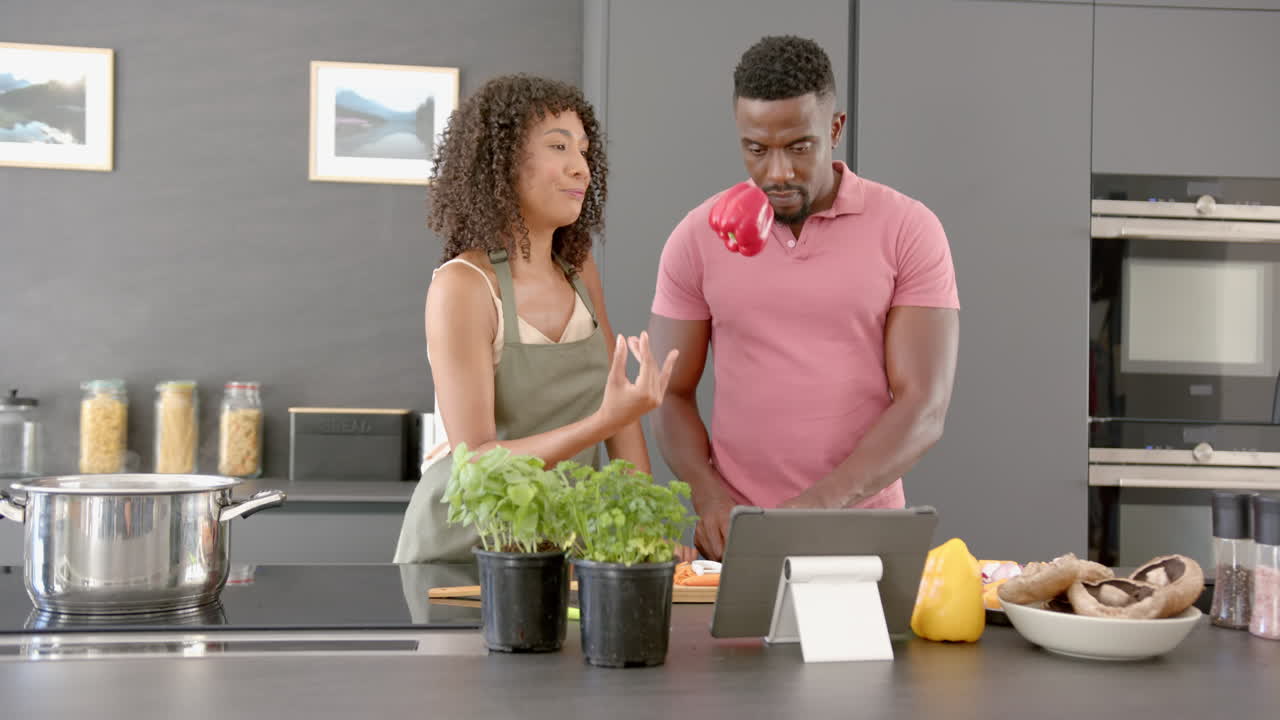 Cooking together in modern kitchen, couple smiling and holding fresh vegetables
