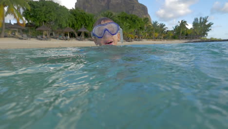 Zeitlupenansicht-Eines-Kleinen-Jungen,-Der-Mit-Der-Schnorchelmaske-Im-Indischen-Ozean-Schwimmt-Und-Ein-Foto-Von-Der-Insel-Port-Louis,-Mauritius-Macht