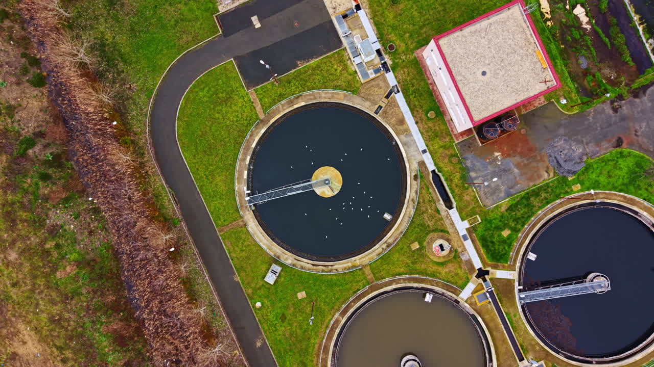 Various types of water treatment tanks at a facility located in a green area near a road taken during the day