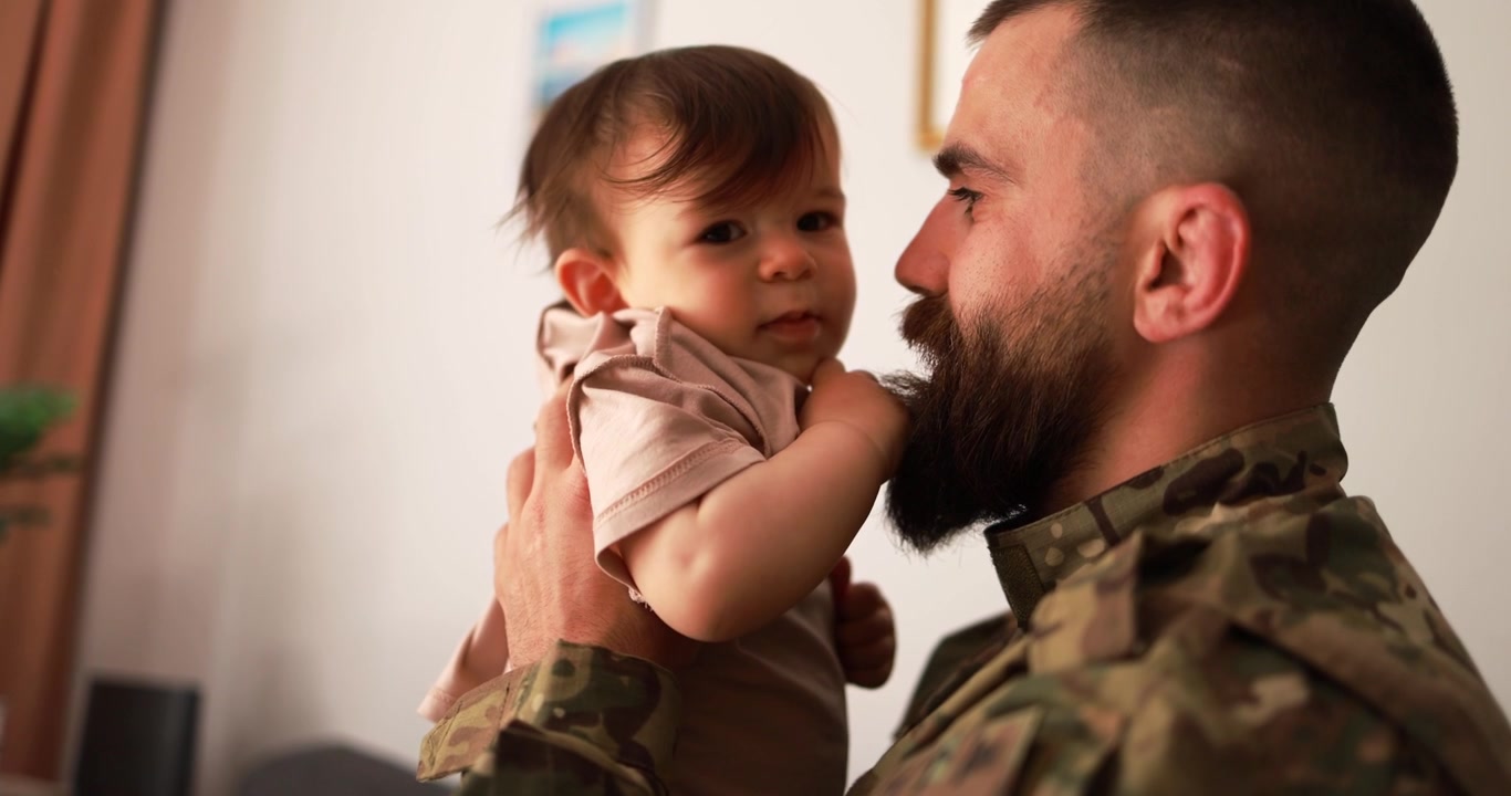 Padre soldato che tiene in braccio il suo bambino che gli tocca la barba