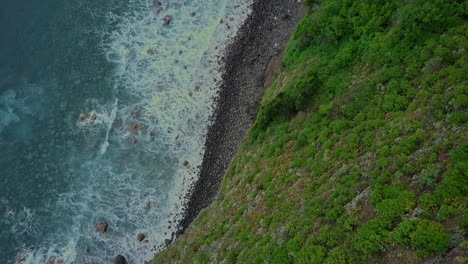 Aerial-panning-up-to-waterfall-flowing-into-Atlantic-Ocean-from-mountainside