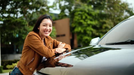 새로운 자동차를 얻은 젊은 아시아 여성은 그의 차를 포옹하고 매우 행복했습니다.