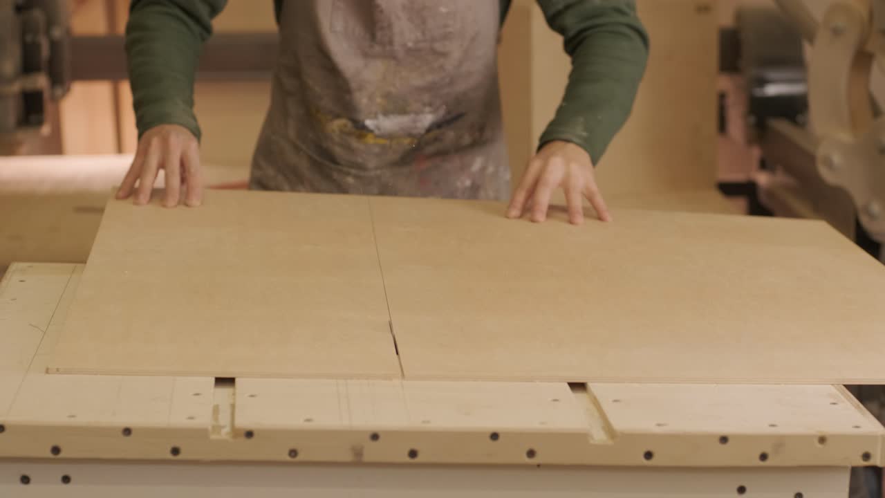 el carpintero corta tabla de madera, panel de contrachapado, madera en bruto en el taller utilizando una máquina de corte