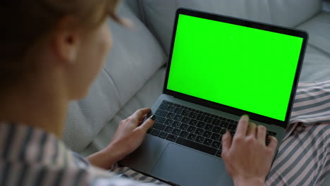 mujer agitando una computadora portátil verde en casa en primer plano. estudiante haciendo videollamadas familiares el fin de semana