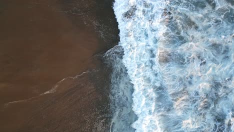 aérea de arriba hacia abajo agua estrellándose en la arena de la playa tropical paraíso