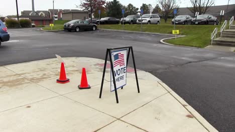 vote aquí firme con la bandera americana que sopla en el viento, ancho