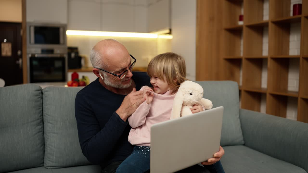 abuelo y hermosa nieta viendo algo juntos por computadora portátil