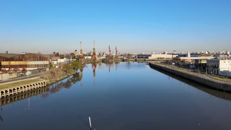 aerial dolly in shot capturing the revitalize waterways from matanza river with industrial port cranes along the riverside in buenos aires