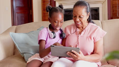 grandmother and granddaughter using tablet at home, sharing joyful conversation