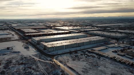 giant warehouses covered with snow in the middle of winter with the rocky mountains in the background