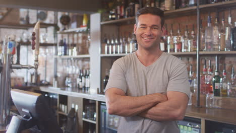 portrait of smiling male bar worker standing behind counter