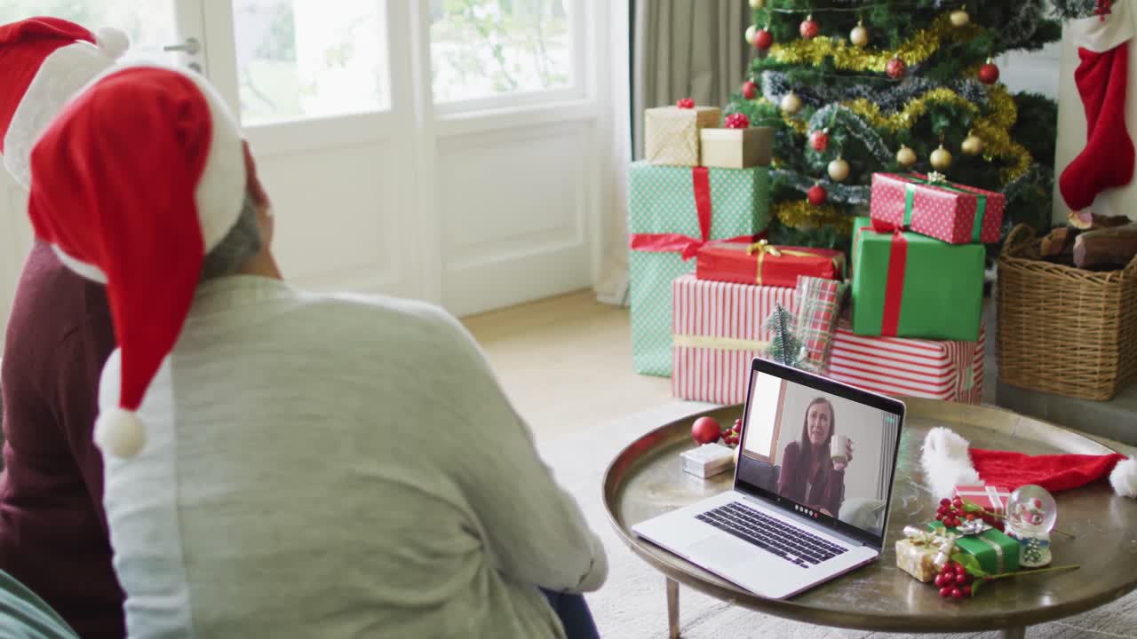 diversas amigas mayores que usan una computadora portátil para una videollamada de navidad con una mujer feliz en la pantalla