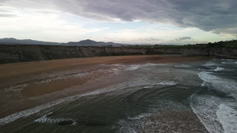 las olas del océano se estrellan contra el acantilado de la playa rocosa en la costa del mar cantábrico