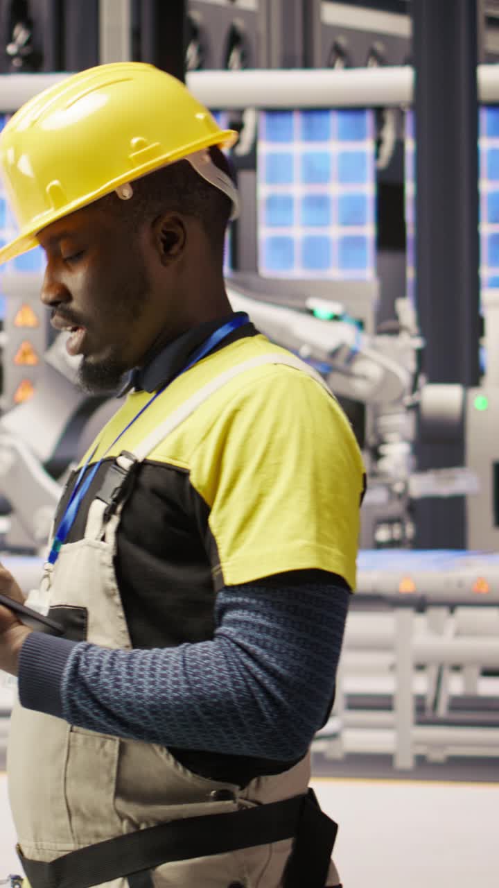 Vertical video Technician in solar panels factory does maintenance using tablet