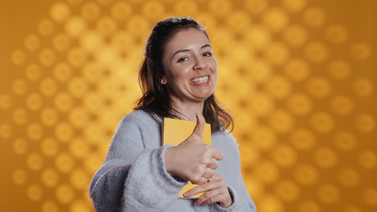 donna felice che parla di un libro fantastico, che mostra il pollice in alto, sullo sfondo dello studio