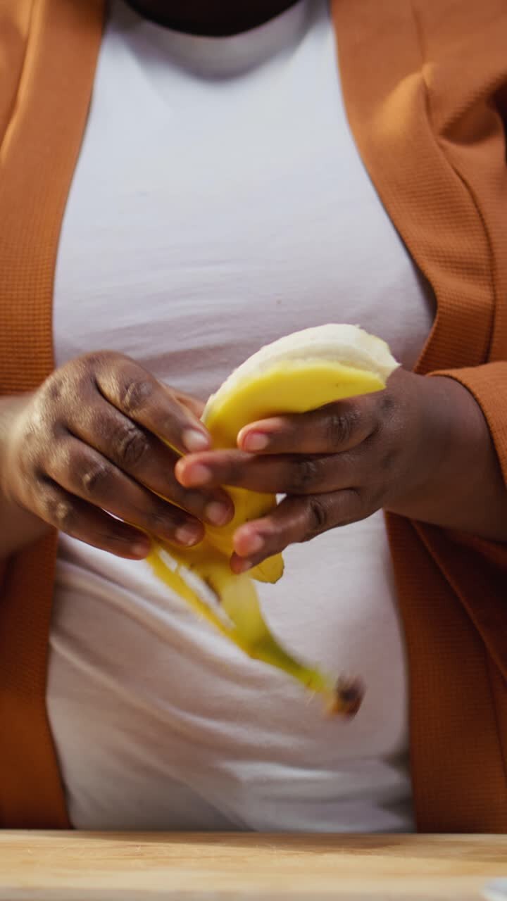 Vertical Video Content creator pealing a banana and adding slices on chia bowl