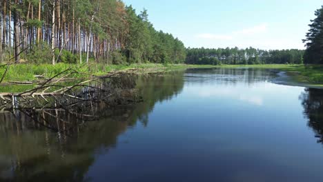 "Drone-soars-over-Europe's-dawn-lit-lake,-revealing-a-tranquil-lagoon,-lush-forest,-and-an-elegant-bridge