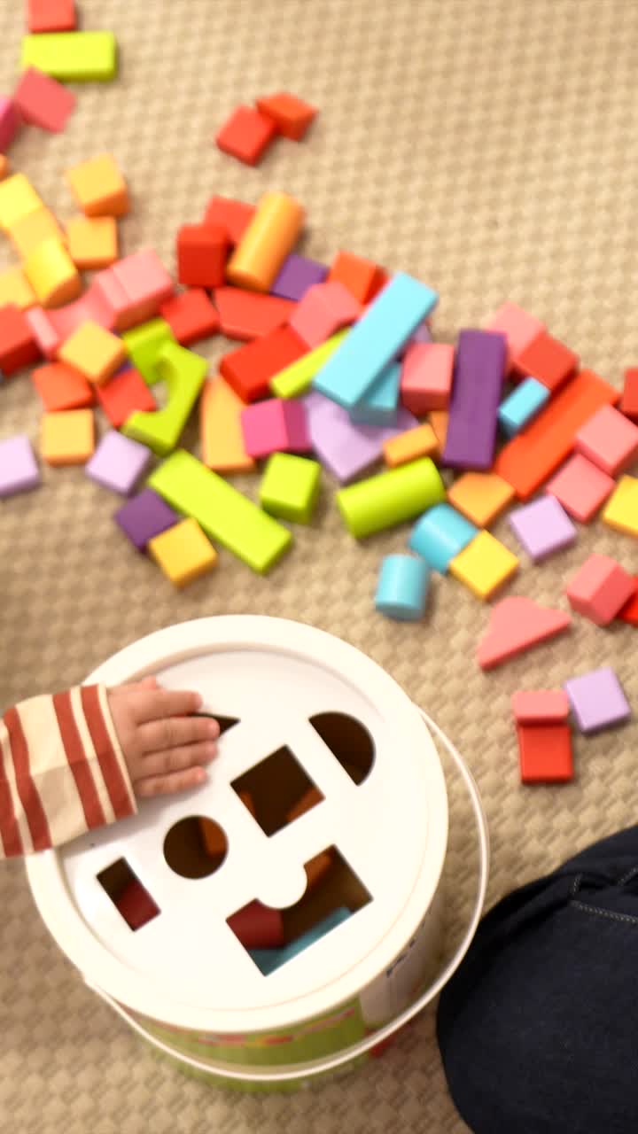 Niño y progenitor jugando con bloques clasificadores de formas de colores.