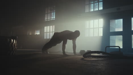 man performing push-ups in a warehouse gym