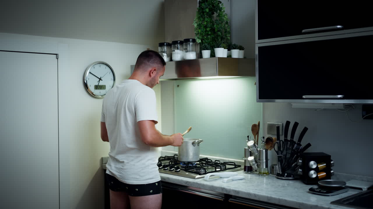Mann som lager grønnsakssuppe på et moderne kjøkken, avslappet atmosfære