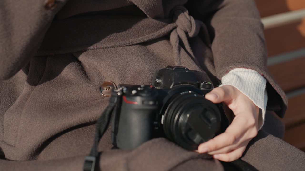 Regolazione dell'obiettivo alla luce del sole. Fotografo professionista che regola l'obiettivo sotto la luce solare. Ispezione meticolosa degli accessori fotografici durante la preparazione di un servizio all'aperto sotto una luce diurna delicata.
