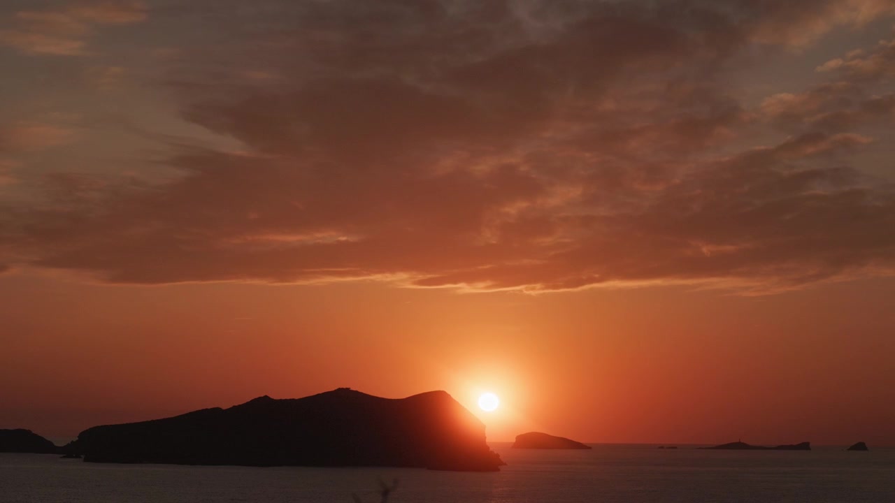 Atardecer dorado sobre la costa de Cala Comte en Ibiza con islas silueteadas y el tranquilo mar Mediterráneo