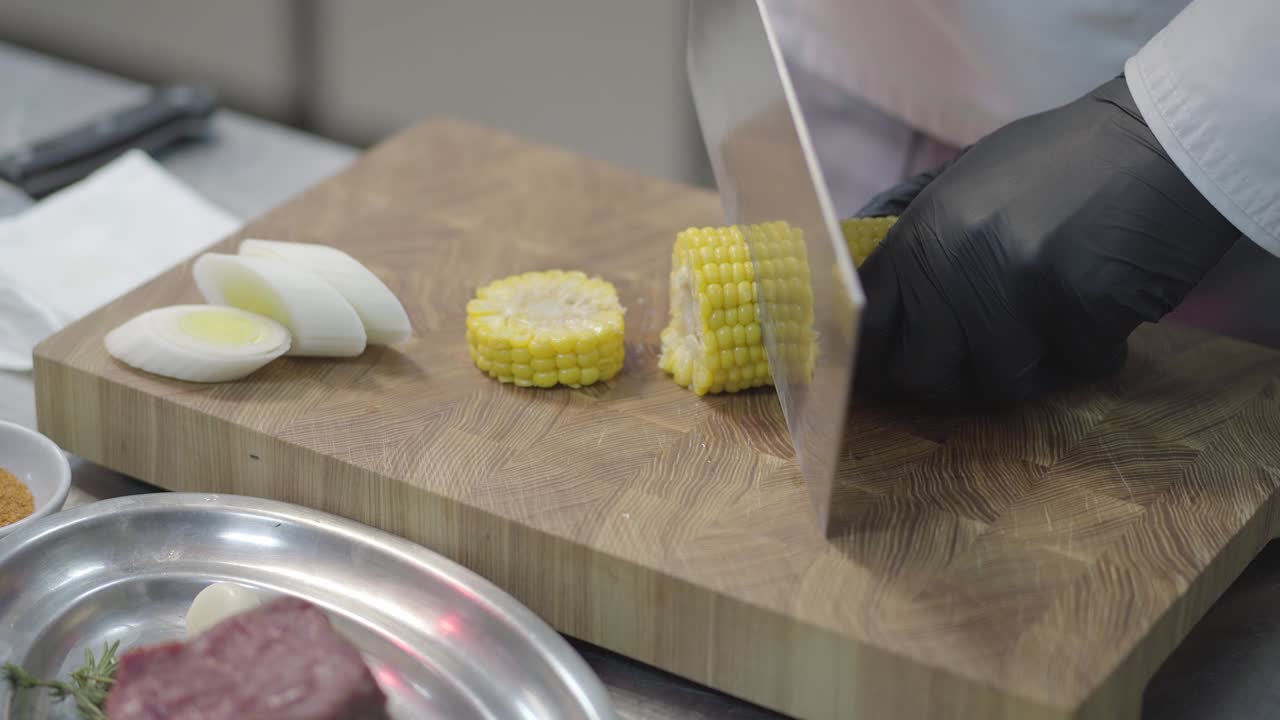 las manos de un profesional no reconocido con guantes negros están cortando maíz.