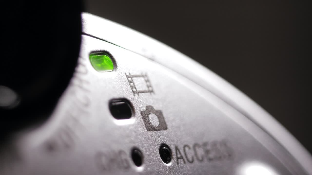 Angled macro of silver camcorder side as green power LED switches on and off