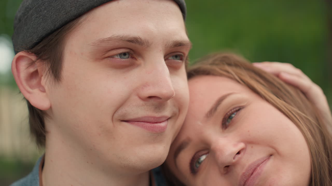 벤치에 앉아 머리를 맞대고 미소 짓는 백인 커플, 남자는 만족한 듯 눈을 감고 여자는 애정 어린 눈빛으로 바라보며, 나무 사이로 쏟아지는 황금빛 햇살, 초록색 공원 배경, 라이프스타일 포트레이트, 편안한 분위기