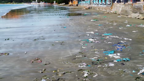 aerial flying over very polluted beach full of dirty plastic trash