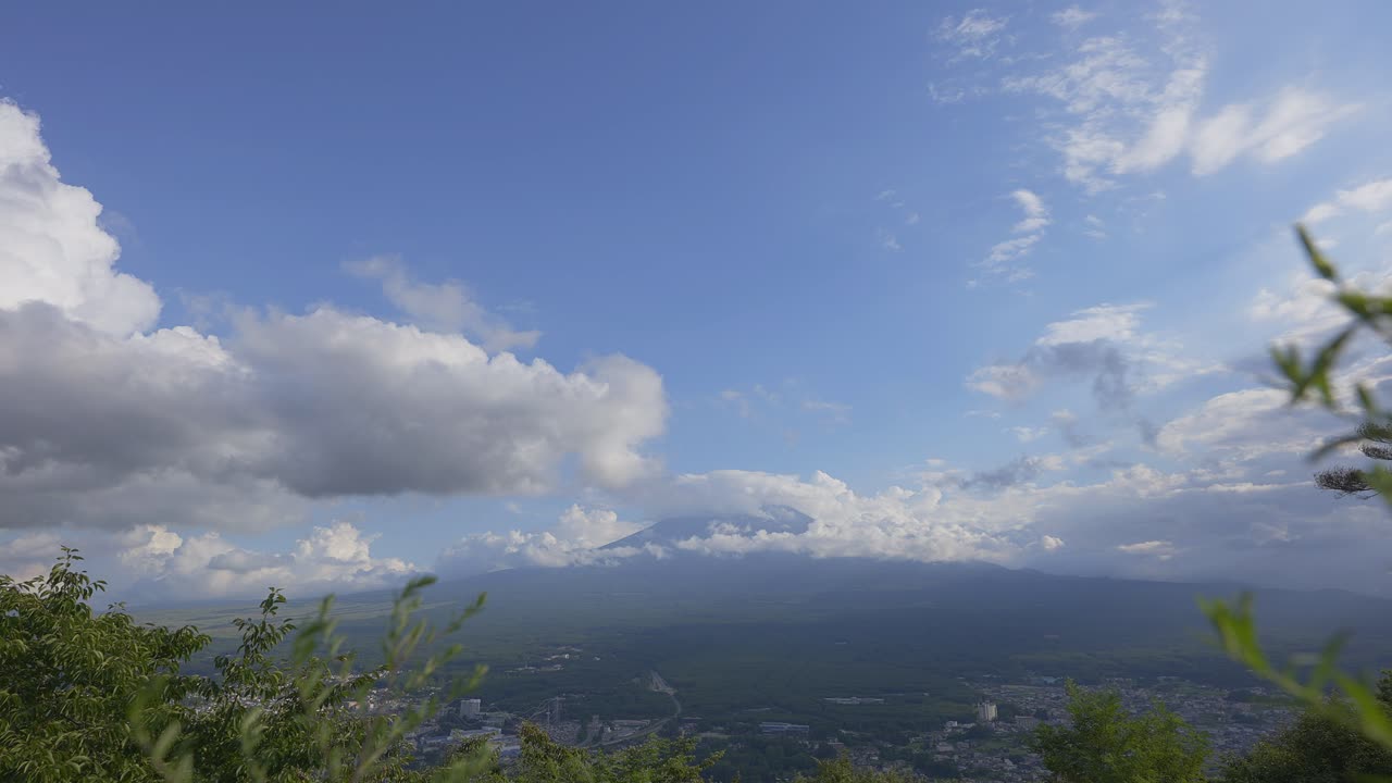 낮에 푸지 산의 숨길 만한 전망을 보라, 그 꼭대기에 지속적이고 거대한 구름이 지배하고, 아래의 도시 풍경을 노출시니다.