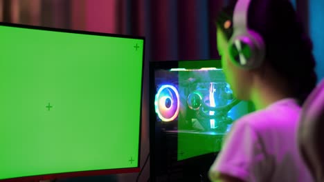 close up of asian teen girl gamer lose while playing video game on computer with mock up green screen