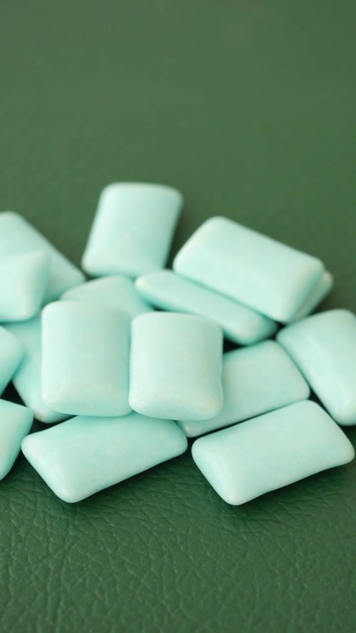 Pila di pezzi di gomma da masticare azzurri su una superficie verde