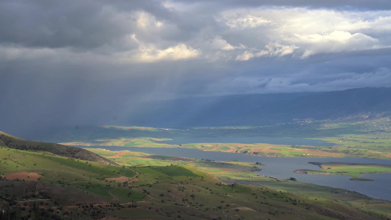 Nuvole temporalesche drammatiche su una valle verde e un lago
