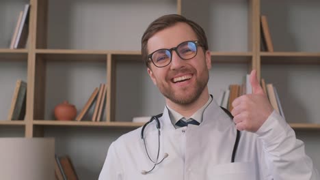 portrait of positive male doctor posing thumbs up and smiling at camera. high quality 4k video