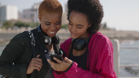 portrait-of-two-beautiful-african-american-woman-uing-phone-on-beachfront-chatting