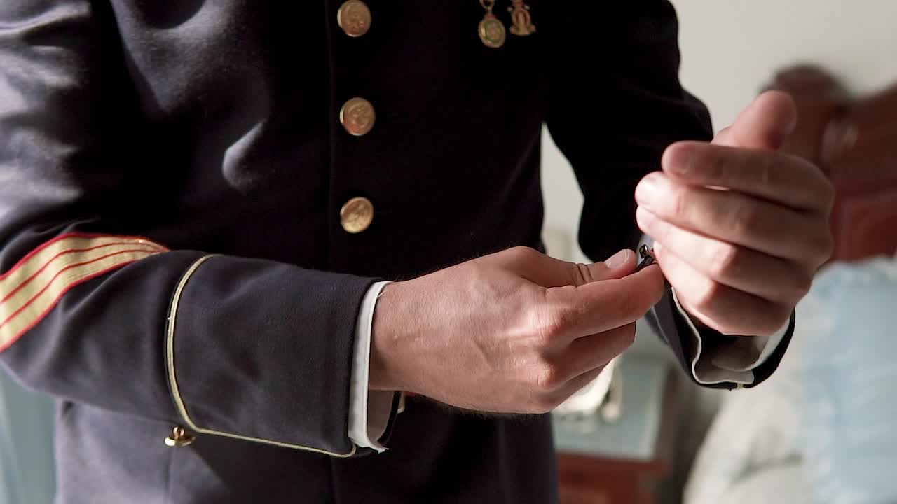 네이비 블루 군복을 입은 신사분이 손목에 시계를 고정하고 있습니다.