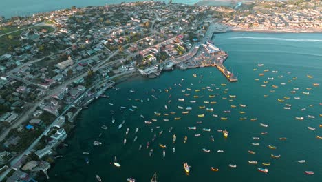 Aerial-orbit-of-Tongoy-peninsula,-with-several-yellow-boats-moored-at-sunset