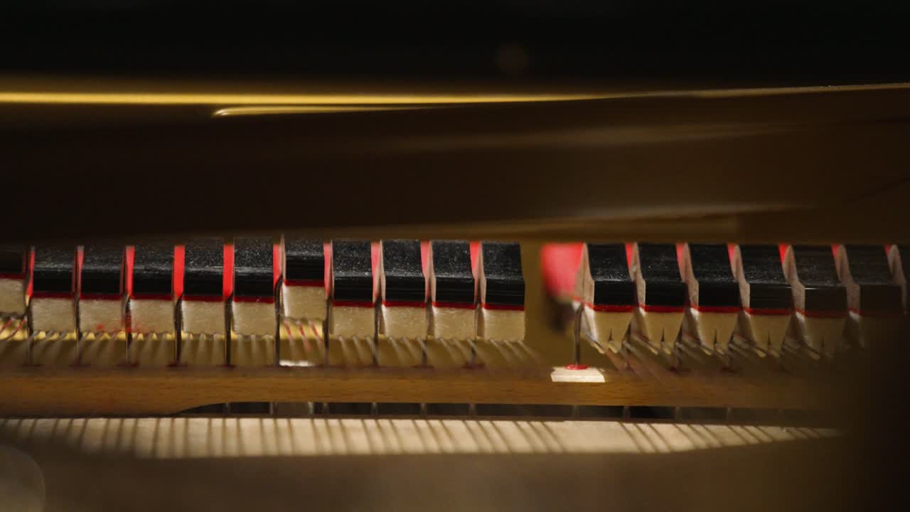 Extreme closeup of an inside of a piano hammers hitting strings with shallow focus in 4k