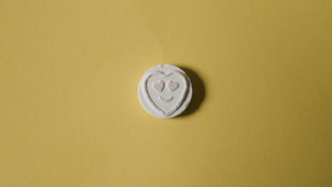 mano recogiendo dulces de corazón con amor emoji sobre fondo amarillo